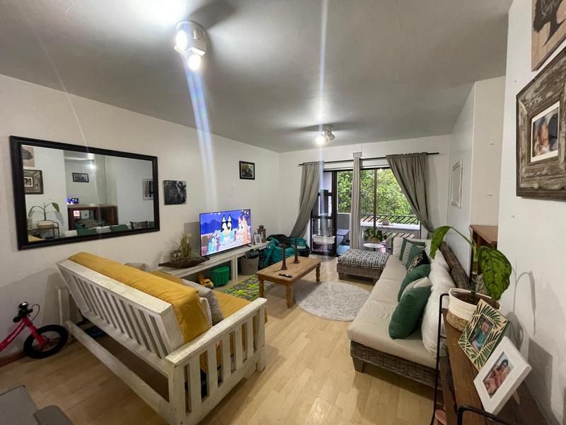 A comfortable living room featuring laminate flooring and a sliding glass door that provides access to an outdoor balcony area.
