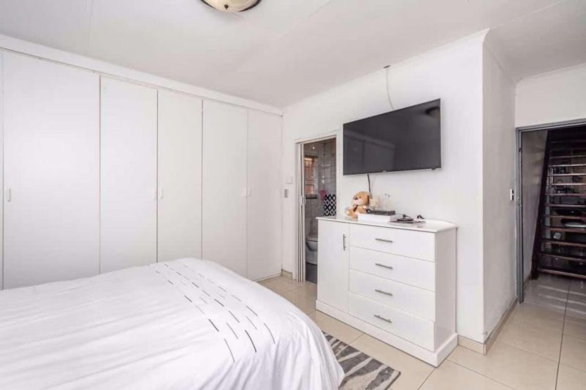 A bedroom featuring built-in cupboards, tiled flooring, and direct access to an en-suite bathroom.