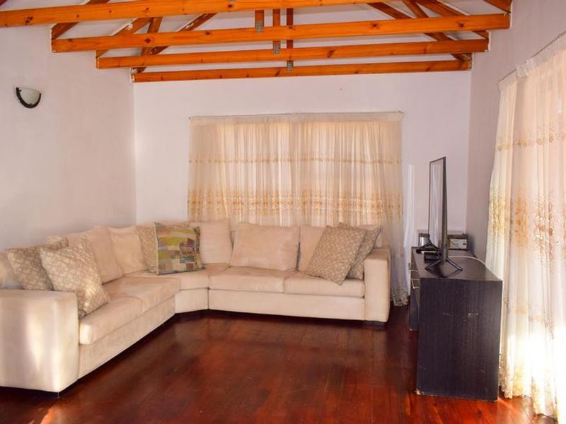 A living room featuring exposed timber ceiling beams and hardwood flooring, offering a rustic foundation ready for modern updates.