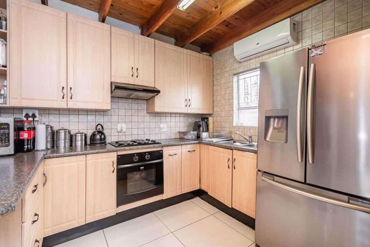 Functional kitchen featuring light wood cabinetry, granite countertops, built-in oven, gas hob, and exposed timber ceiling beams.