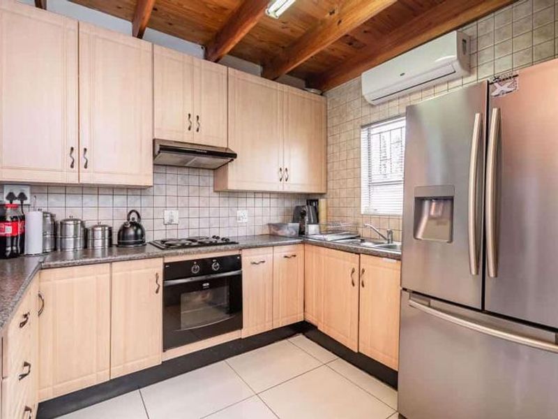 Functional kitchen featuring light wood cabinetry, granite countertops, built-in oven, gas hob, and exposed timber ceiling beams.