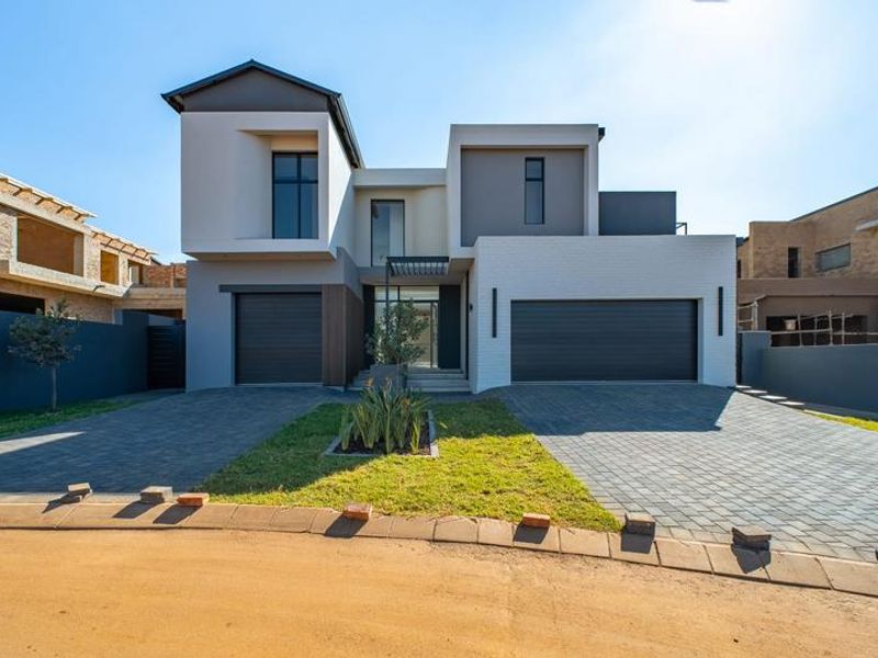 Modern double-story residential property featuring a contemporary facade, double garage, and paved driveway in a newly developed estate.