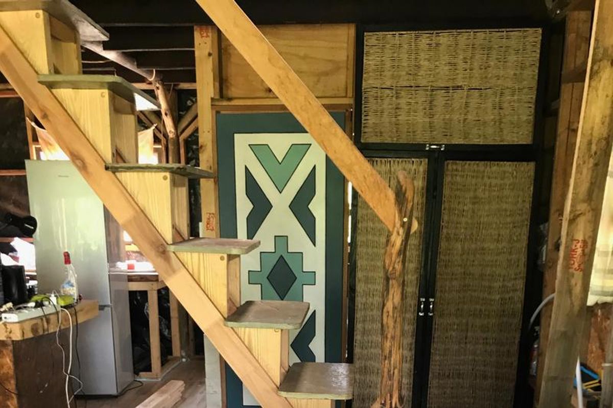 Interior view showing a rustic wooden staircase and built-in cabinetry within an unfinished farm-style living space.