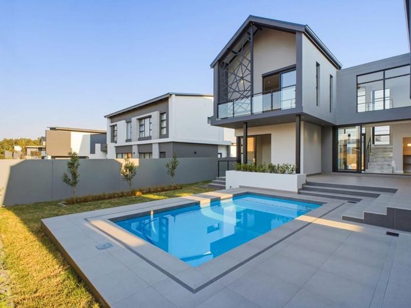 Modern rear exterior featuring a swimming pool, tiled patio area, and contemporary architectural design with large glass sliding doors.