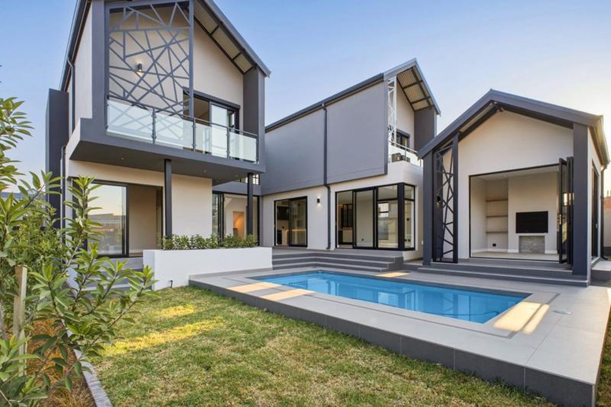 Modern rear exterior featuring a swimming pool, tiled deck, contemporary architectural design with glass balustrades, and seamless indoor-outdoor flow through large sliding doors.