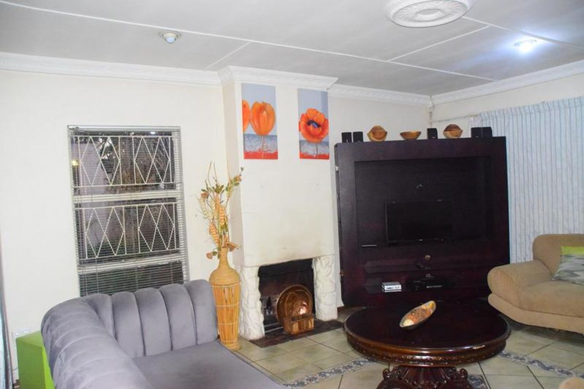 A living room featuring a fireplace, tiled flooring, and decorative ceiling detailing, providing a functional and comfortable space.