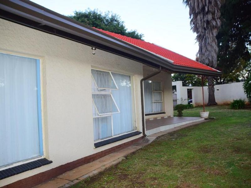 Rear view of the house featuring a tiled roof, covered patio area, and established garden space with aluminium window frames.