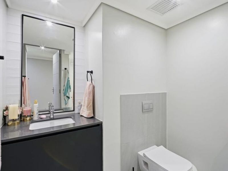 Modern bathroom featuring a sleek vanity with undermount sink, framed mirror, and a wall-hung toilet with a concealed cistern.