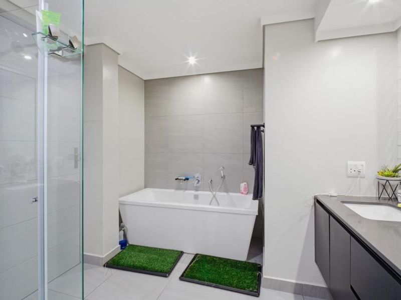 Modern bathroom featuring a sleek freestanding bathtub, glass-enclosed shower, and a contemporary vanity with an undermount sink and stone countertop.
