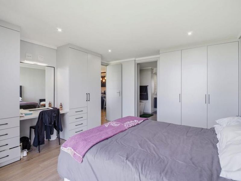 A well-maintained bedroom featuring extensive built-in cabinetry, a dedicated vanity area, recessed lighting, and modern laminate flooring.