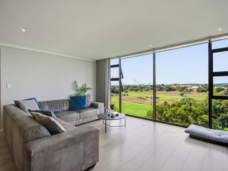 A bright and modern living room featuring expansive floor-to-ceiling windows that offer scenic views and abundant natural light.
