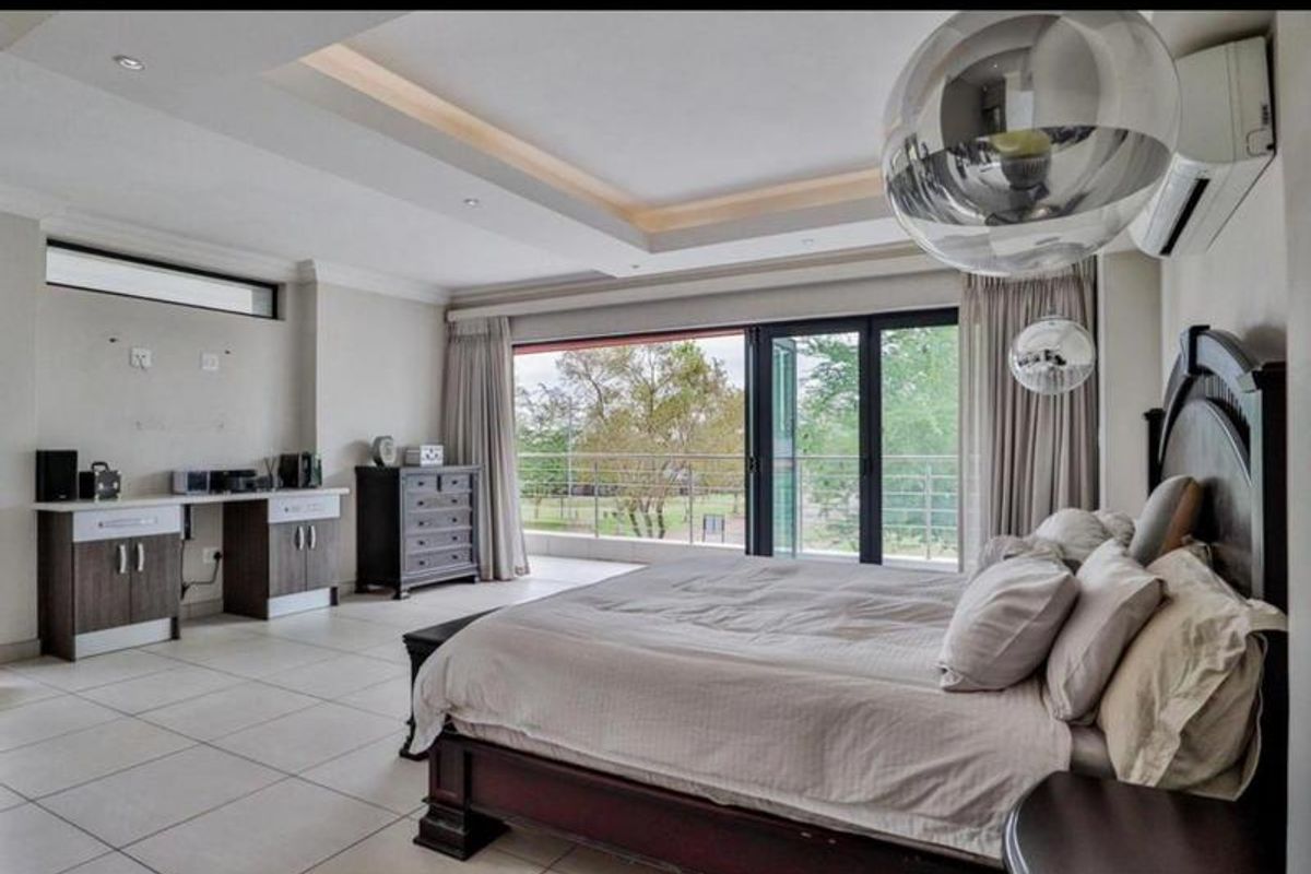 Spacious bedroom featuring a tray ceiling with recessed lighting, built-in cabinetry, tiled floors, and large sliding glass doors opening to a private balcony.