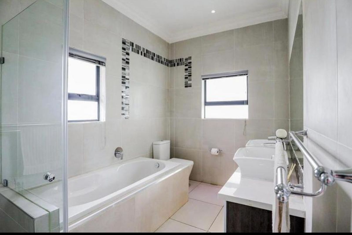 Modern bathroom featuring a built-in bathtub, glass shower enclosure, and a dual vanity with contemporary basins and cabinetry.