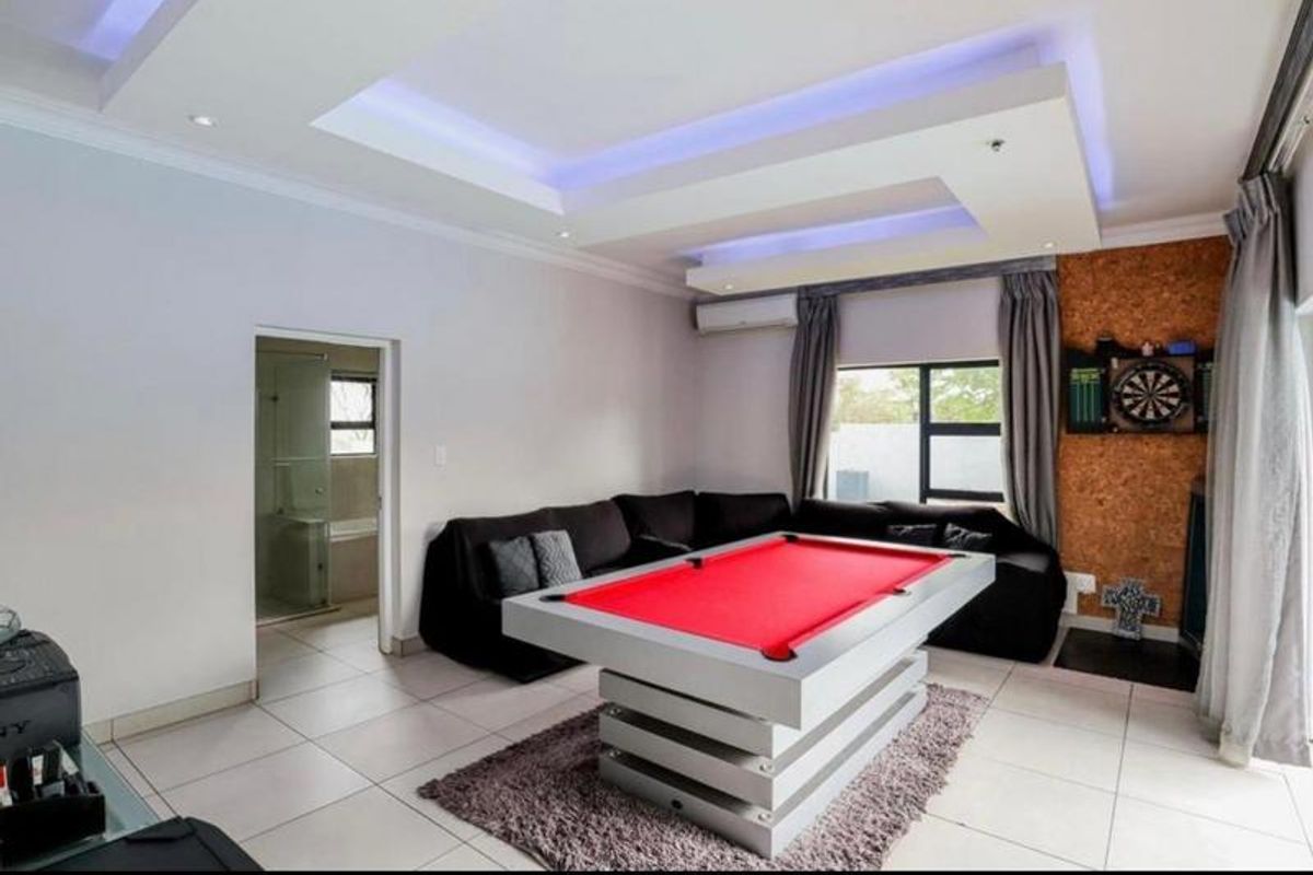 Spacious living area featuring a modern recessed ceiling with integrated LED lighting, tiled flooring, and a split-system air conditioner, with an adjoining bathroom.