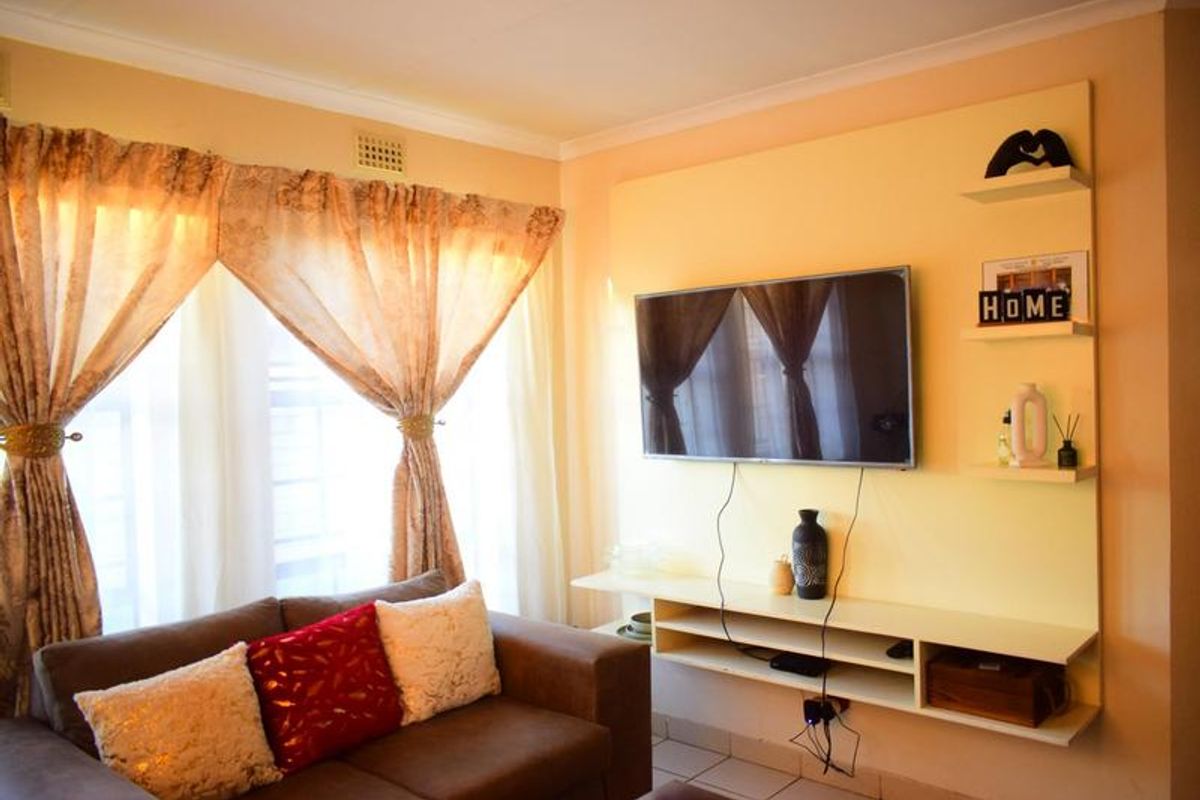 A living room featuring a built-in media console with floating shelving and decorative coving.