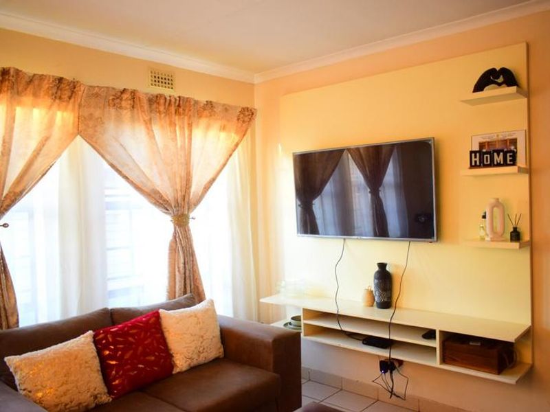 A living room featuring a built-in media console with floating shelving and decorative coving.