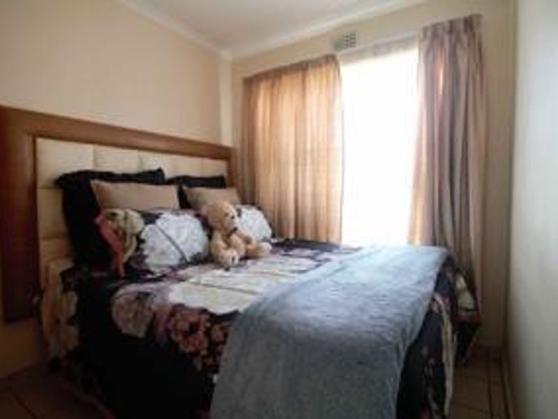 A standard bedroom featuring a built-in headboard and window with curtain rails, providing a functional sleeping space.