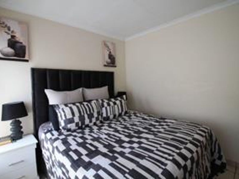 A neutrally painted bedroom featuring coving and a standard layout, providing a clean and functional space for rest.