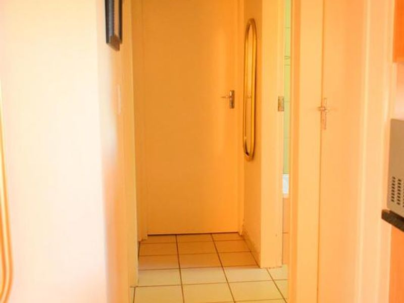 A functional hallway featuring neutral tiled flooring and access to multiple rooms, providing a clean and simple transition space within the home.