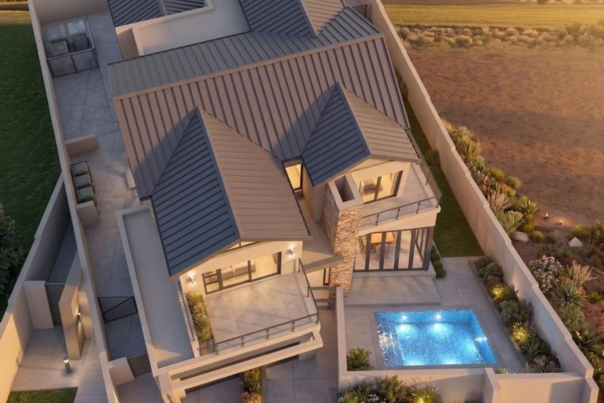 Aerial view of a modern residential property featuring a metal roof, swimming pool, stone accents, and landscaped outdoor areas at sunset.