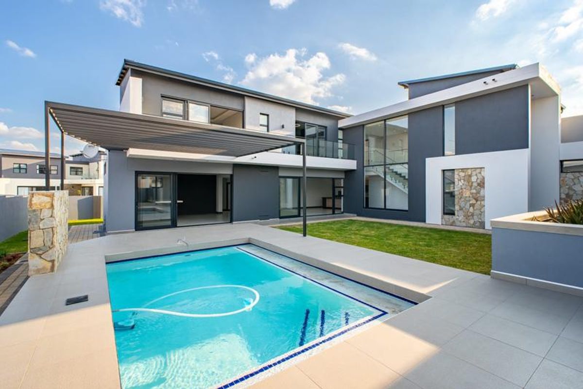 Modern double-story residence featuring a rear garden, swimming pool, tiled patio area with pergola, and contemporary stone and render facade finishes.