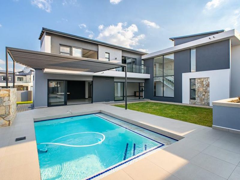 Modern double-story residence featuring a rear garden, swimming pool, tiled patio area with pergola, and contemporary stone and render facade finishes.