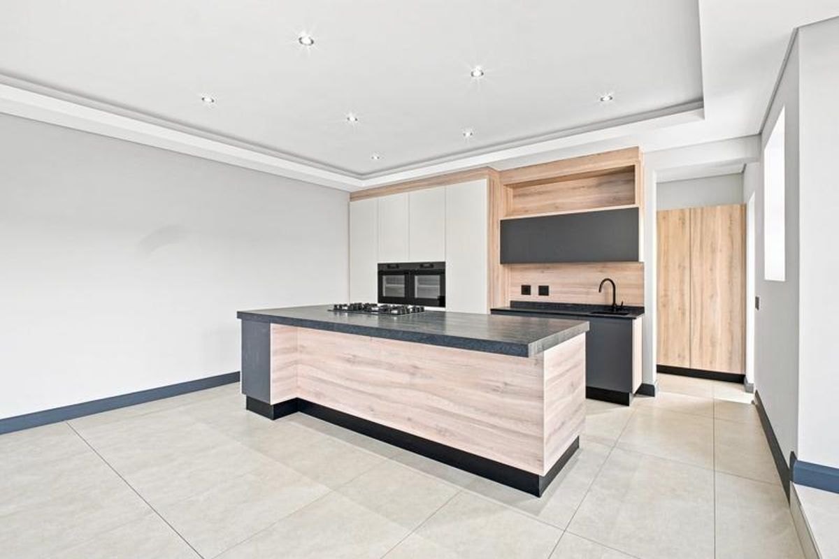 Modern kitchen featuring a central island, built-in oven, gas cooktop, sleek cabinetry, and high-quality tiled flooring in a bright, open-plan space.