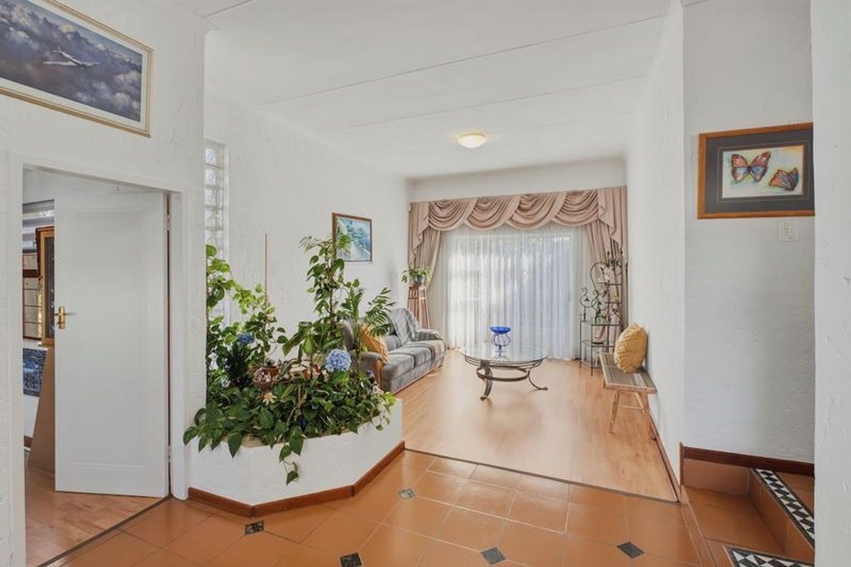 Spacious living area featuring a unique built-in planter, glass block accents, and a combination of terracotta and laminate flooring leading to a sliding door.