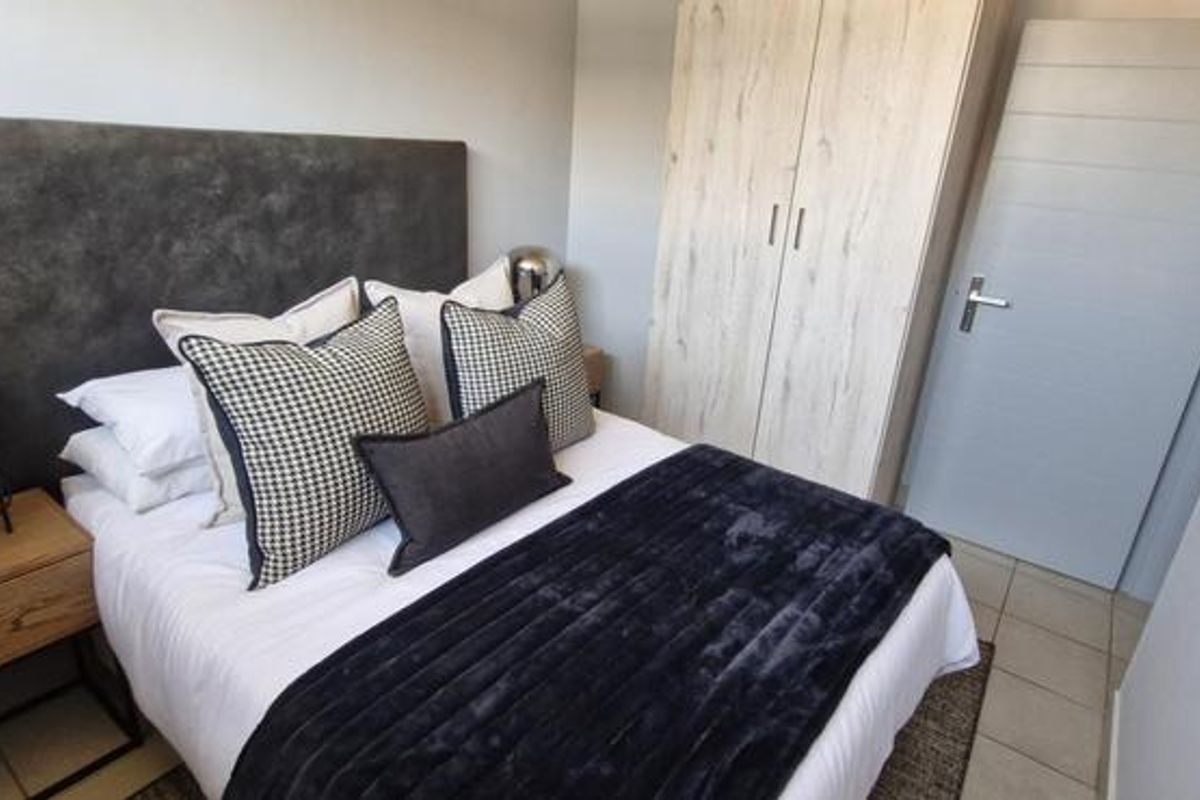 A well-maintained bedroom featuring neutral tiled flooring, a built-in wardrobe with wood-grain finish, and a modern internal door.