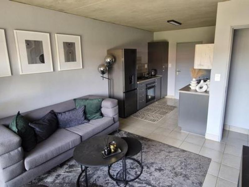 An open-plan living area featuring tiled flooring and a compact kitchen with built-in cabinetry and oven, creating a functional and modern living space.