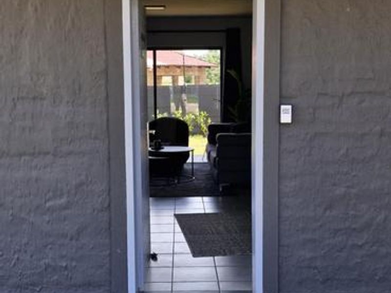 A view of the apartment entrance featuring a tiled porch, exterior lighting, and a secure doorway leading into the living area.