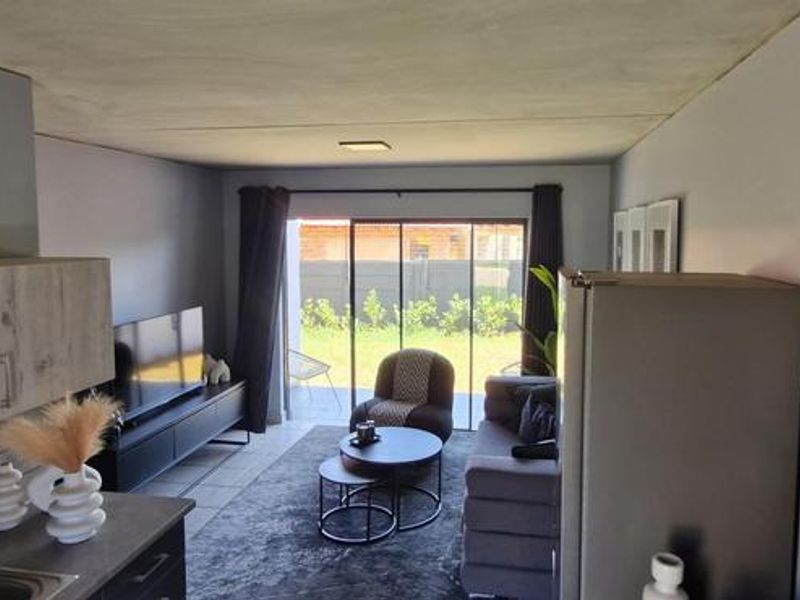 Open-plan living area featuring a compact kitchen with modern cabinetry and a sliding glass door providing direct access to the outdoor space.