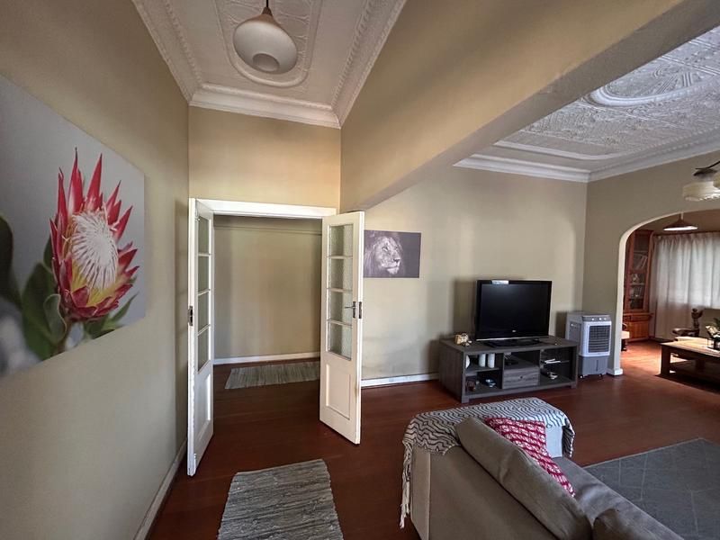 Spacious living area featuring classic ornate plaster ceilings, hardwood flooring, and an elegant archway leading to an adjacent room.