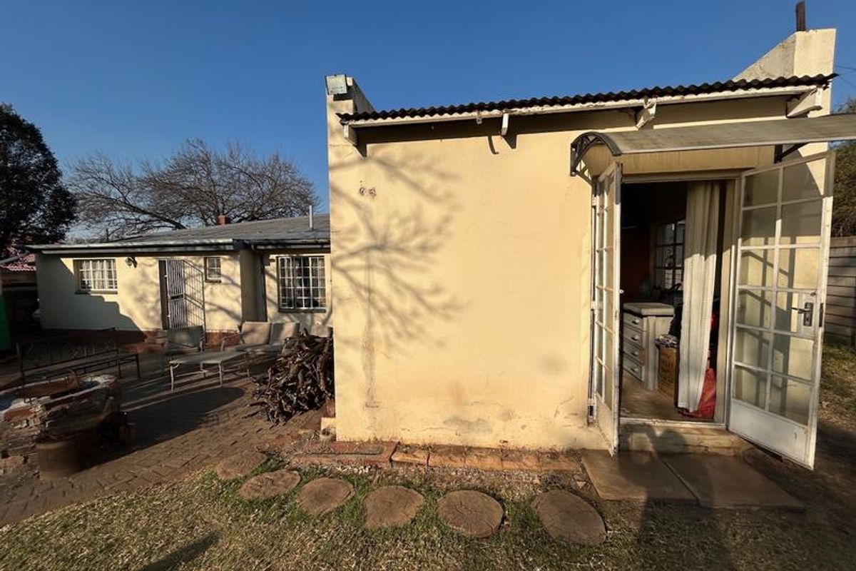 Rear view of the property featuring a brick paved patio area, corrugated metal roofing, and french door access to the interior.