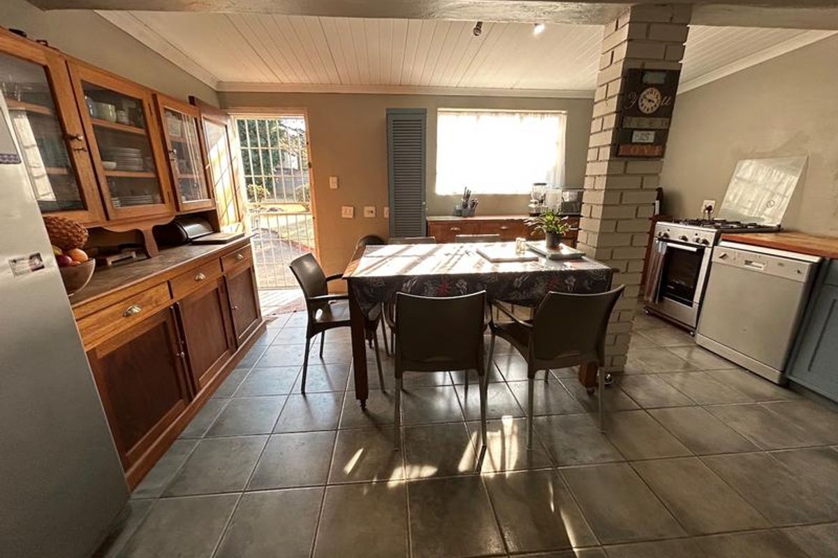 A functional kitchen featuring built-in wooden cabinetry, tiled flooring, a brick support pillar, and integrated appliances including a stove and dishwasher.