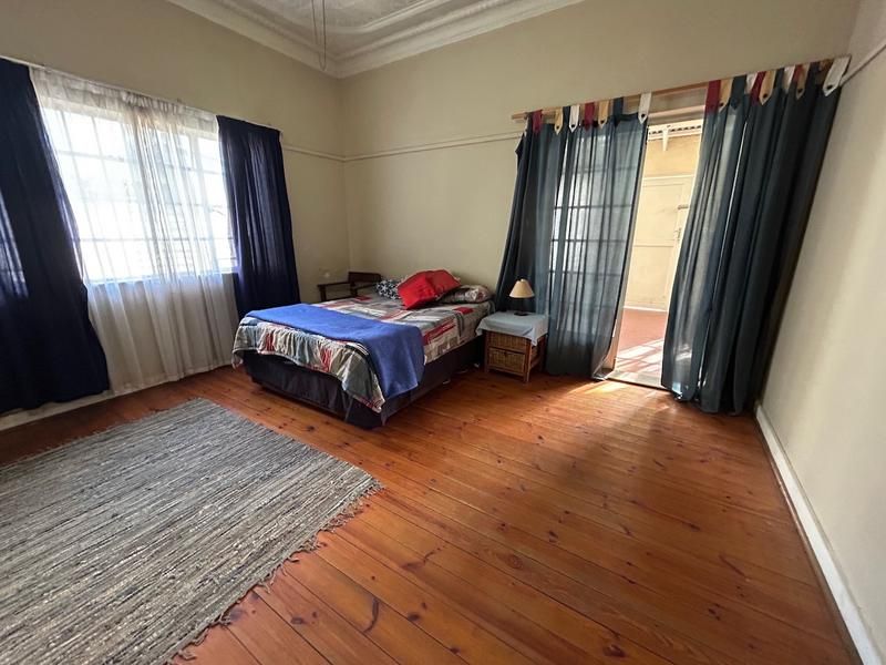 Spacious bedroom featuring original hardwood flooring, ornate ceiling detailing, and direct access to an outdoor area through classic french doors.