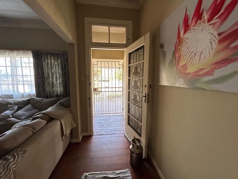 Entrance area featuring a classic leaded glass front door with transom window, opening onto a secure exterior gate and hardwood flooring.