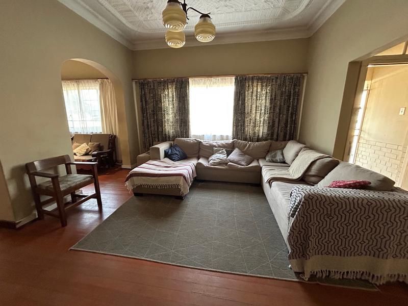 Spacious living room featuring original pressed metal ceilings, hardwood flooring, and an inviting archway leading to an adjacent area.