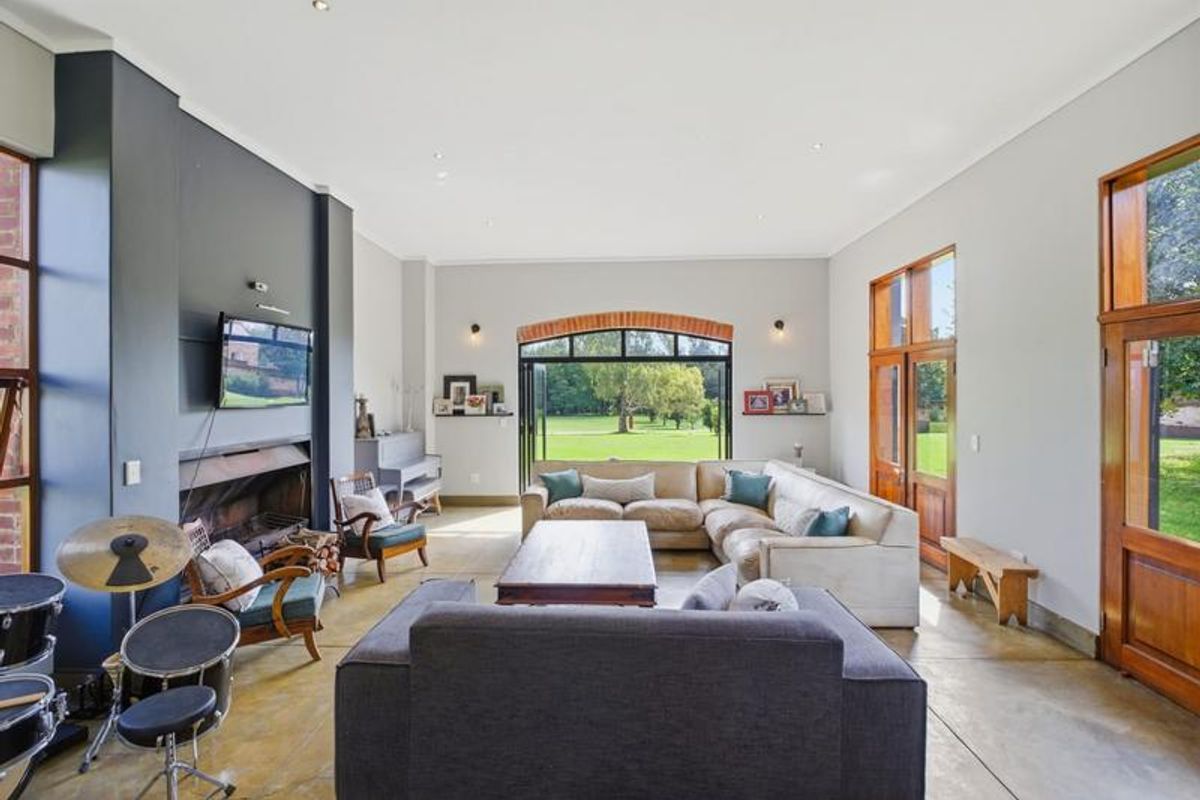 Spacious living room featuring polished concrete floors, a built-in fireplace, and large bi-fold doors opening onto the garden with an exposed brick arch detail.