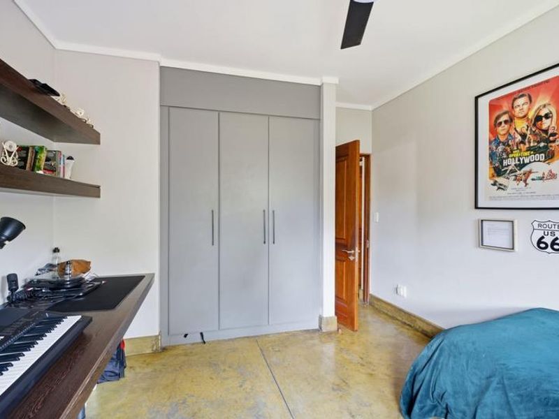 A well-maintained bedroom featuring polished concrete floors, built-in grey cabinetry, and a ceiling fan, offering a modern and functional living space.