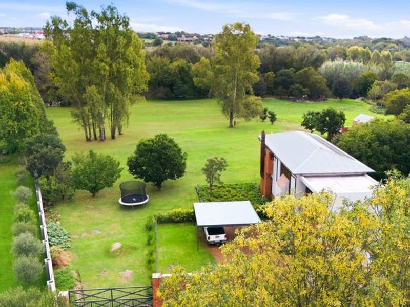 Aerial view of the small holding property featuring a spacious garden, metal roof dwelling, and a covered carport area.