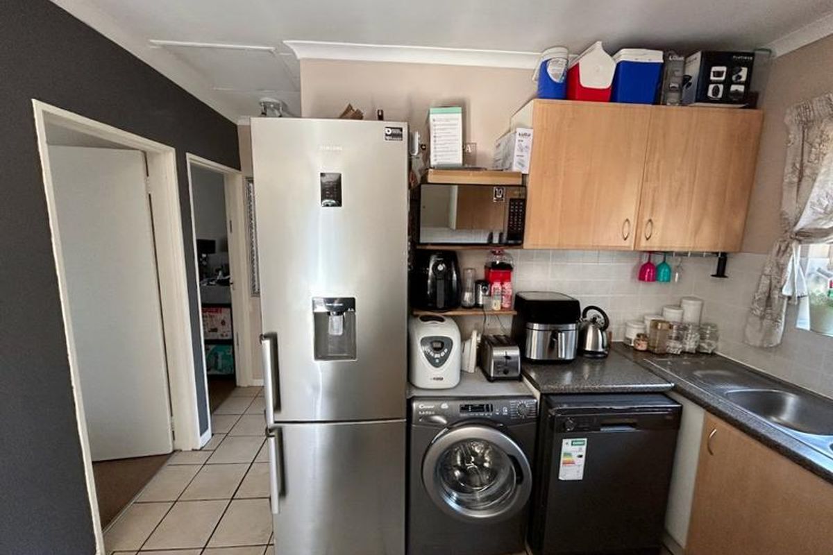A functional kitchen area featuring built-in cabinetry, laminate countertops, a stainless steel sink, and tiled flooring, providing essential utility space.