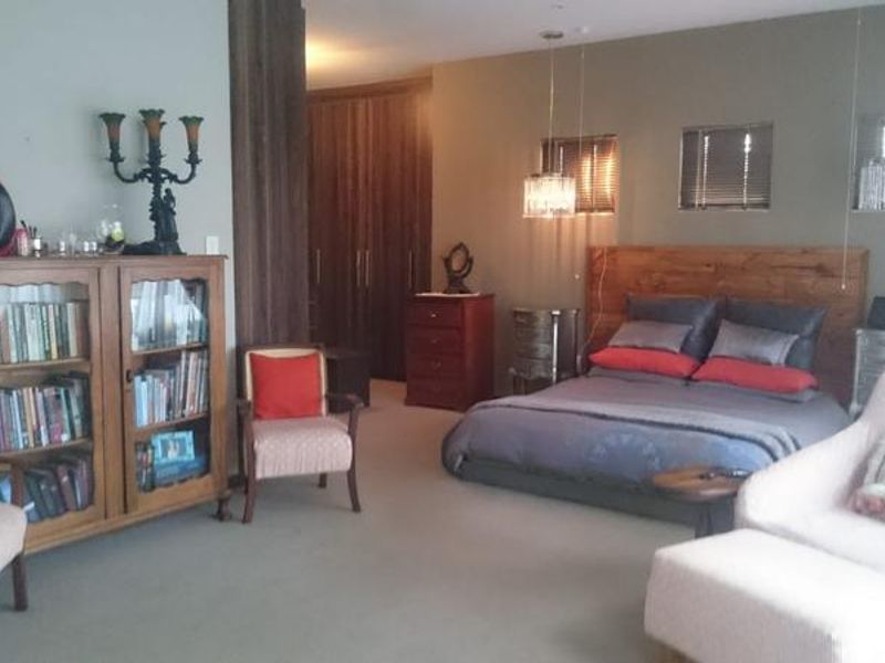 Spacious bedroom featuring built-in cupboards, a timber headboard, and modern pendant lighting, offering a comfortable and well-maintained living space.