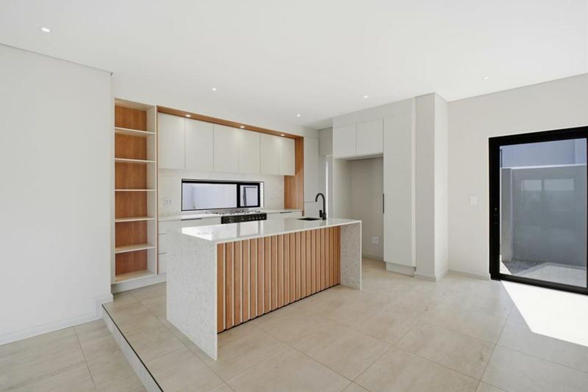 Modern kitchen featuring a central island with stone countertops, sleek cabinetry, integrated shelving, and high-quality finishes in a bright, open-plan layout.