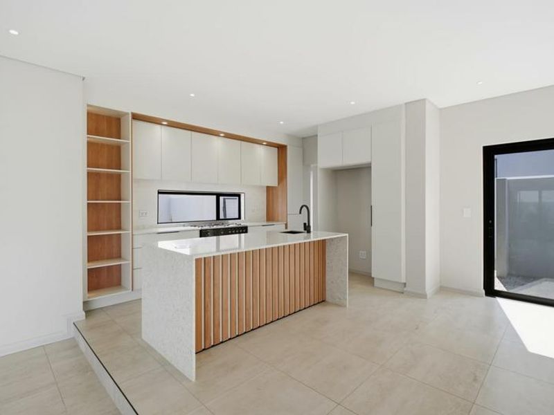 Modern kitchen featuring a central island with stone countertops, sleek cabinetry, integrated shelving, and high-quality finishes in a bright, open-plan layout.