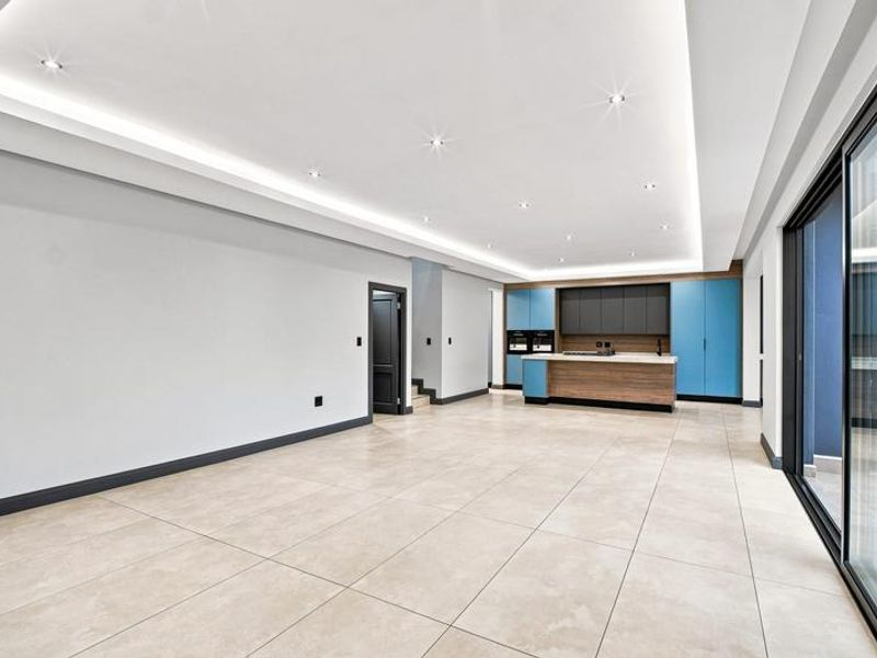 Spacious open-plan living and kitchen area featuring modern cabinetry, a central island, recessed lighting, and large sliding glass doors leading to the exterior.