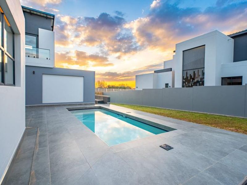 Modern outdoor pool area featuring a sleek tiled deck, glass balustrades, and contemporary architectural design, perfect for relaxation and entertaining.