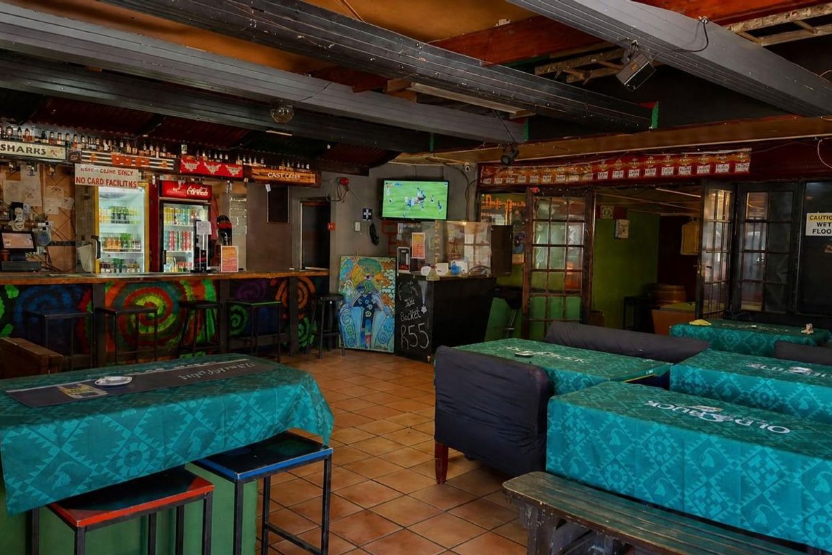A rustic bar area featuring a built-in counter, exposed timber ceiling beams, and tiled flooring, offering a casual atmosphere for patrons.