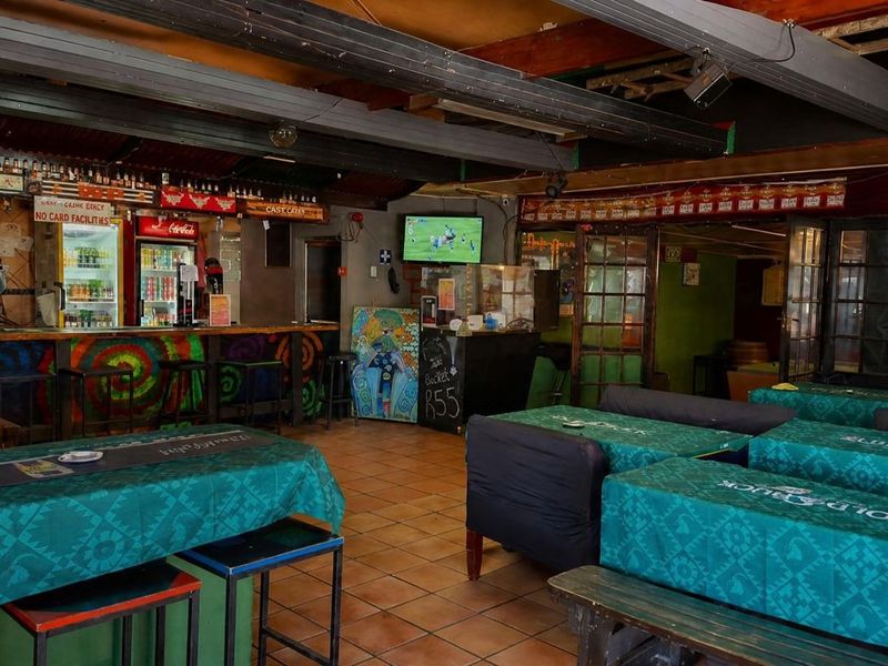 A rustic bar area featuring a built-in counter, exposed timber ceiling beams, and tiled flooring, offering a casual atmosphere for patrons.