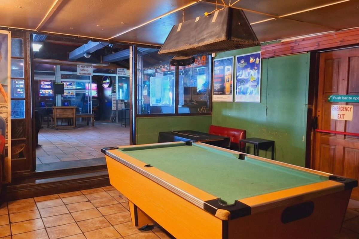 A functional bar area featuring tiled flooring, a glass partition, and an emergency exit, providing a casual space for entertainment.